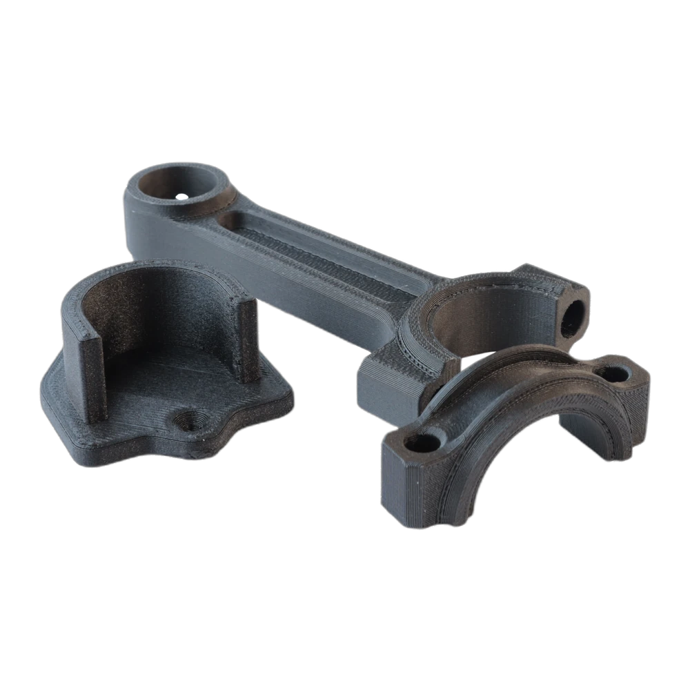 A set of black 3D-printed polycarbonate engineering brackets and a connecting rod printed in 3DXTech PC