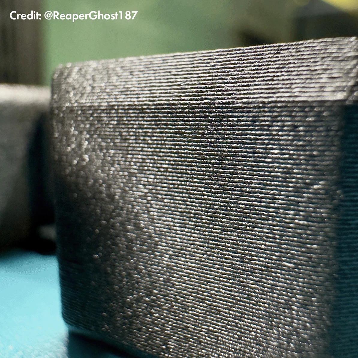 Extreme macro of a 3DXTech CarbonX PETG+CF printed part showing fine carbon-fiber speckle and matte texture