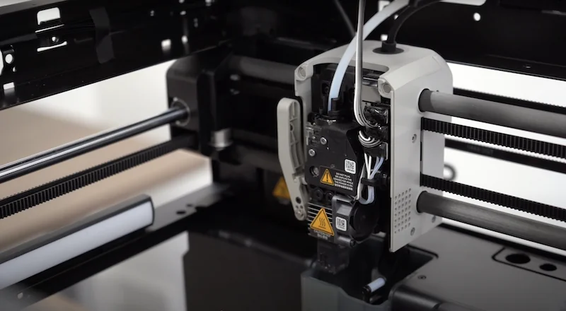 Close-up of the Bambu Lab P1P CoreXY gantry — carbon rods, belts and the moving toolhead