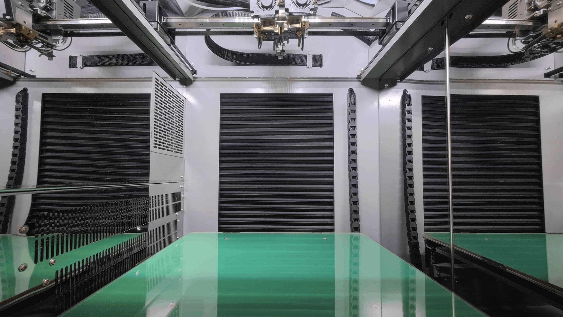 CreatBot PEEK-300 interior — green PEI build plate and insulated heated chamber walls with the dual print head above