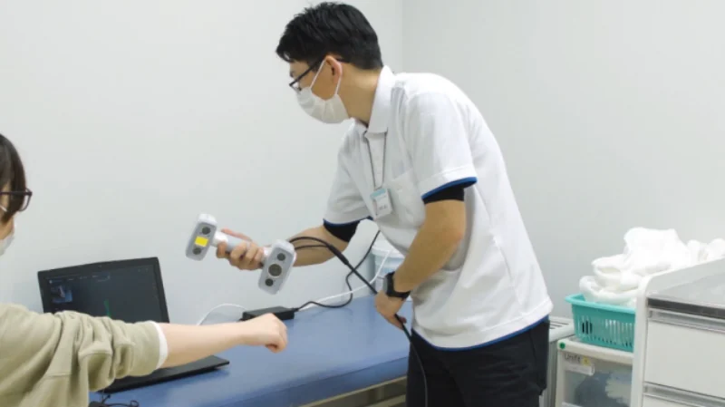 Clinician using the EinScan H2 handheld scanner to capture a patient's arm in a medical clinic