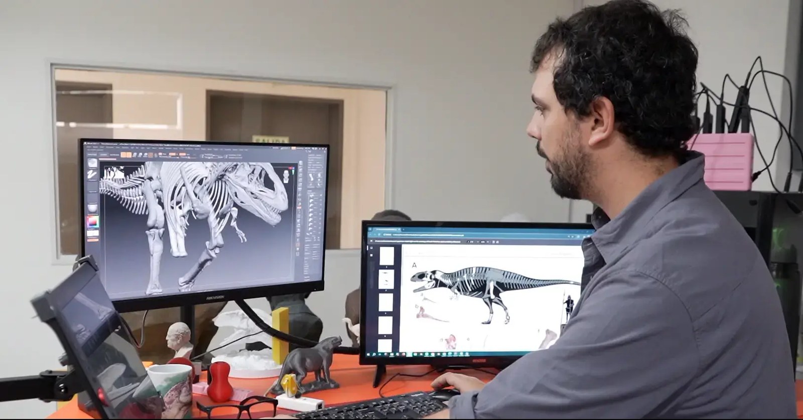 Designer at a workstation refining a dinosaur-skeleton 3D model captured with the EinScan Pro HD