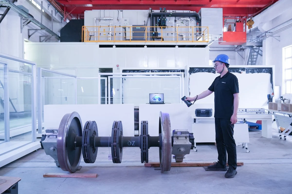 Technician scanning a railway wheelset and axle in a workshop