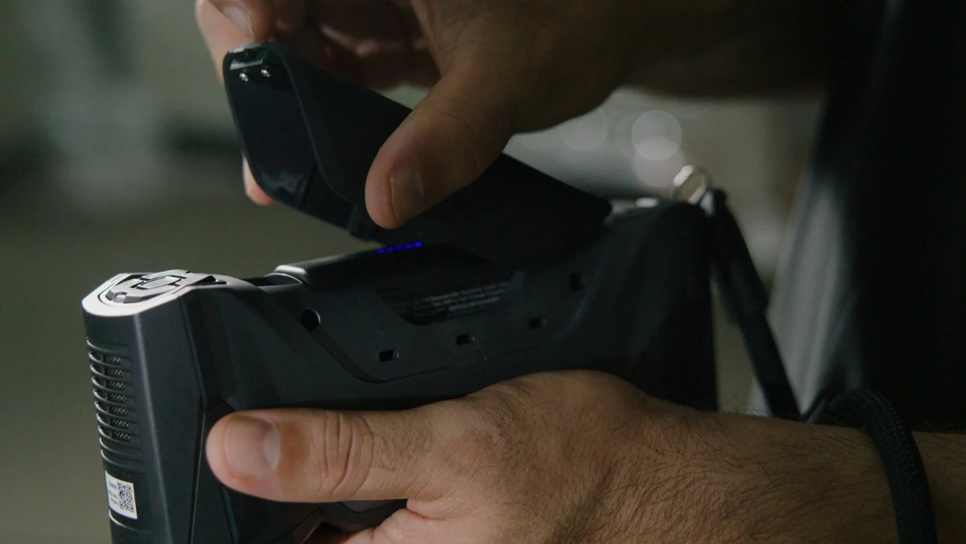 Hands sliding a charged battery pack into the grip of a FreeScan Combo+ Wireless