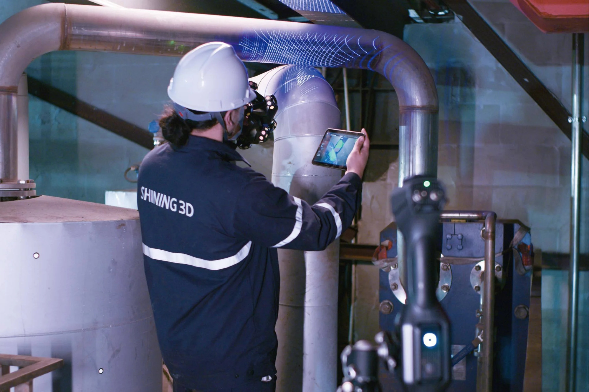 Technician wirelessly scanning overhead pipework while holding a tablet