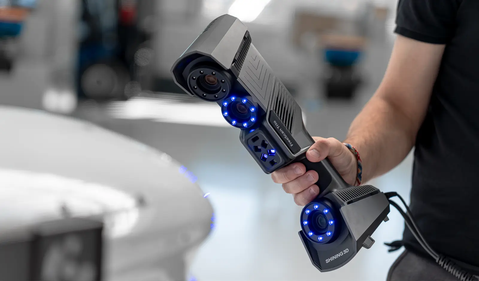 Shining 3D FreeScan Trio hardware close-up &mdash; triple-camera pod chassis with blue LED tracking rings and SHINING 3D branding, shown scanning the NSU Prince automotive surface