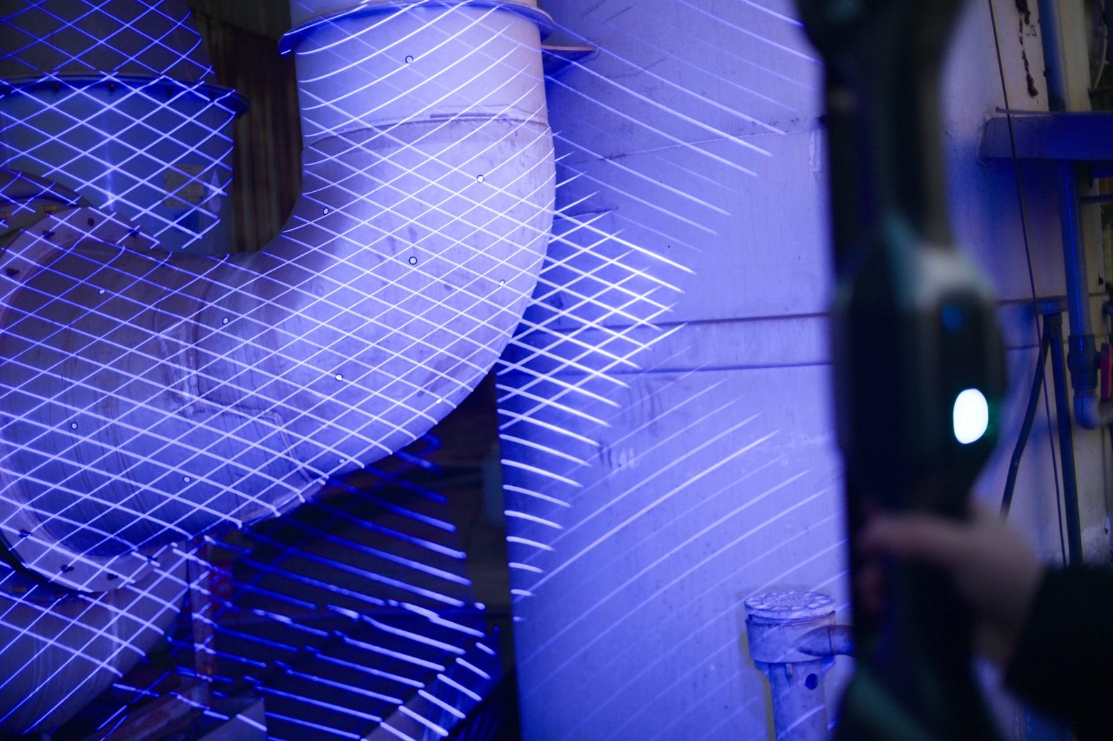 FreeScan UE Nova projecting 50 parallel blue-laser lines across industrial ductwork to build a live scan mesh