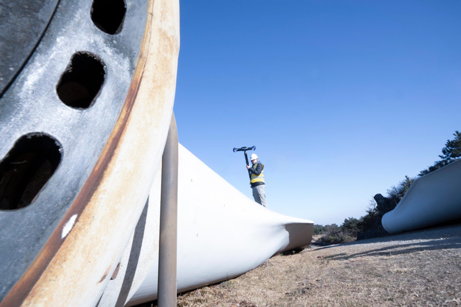 Operator scanning a large wind-turbine blade outdoors with the FreeScan UE Nova, the FreeScan family step-up for large assets