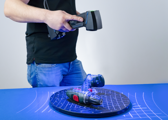 FreeScan UE Pro scanning a part on a turntable with crossed blue-laser lines across its three scanning modes