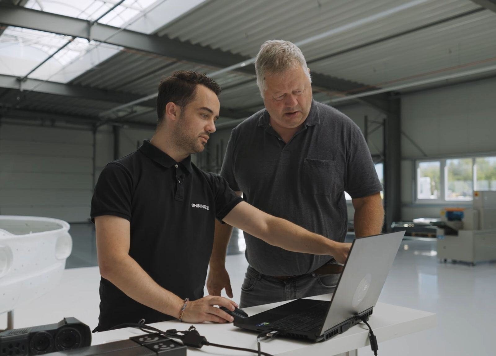 SHINING 3D specialist reviewing FreeScan UE Pro scan results on a laptop with the wireless scanner on the workshop bench