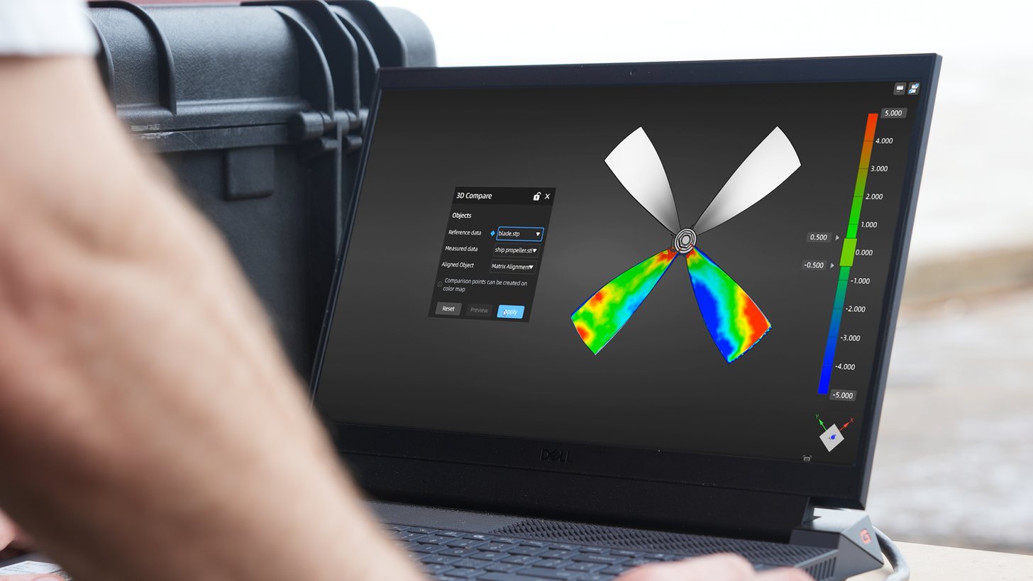 Part-to-CAD deviation color map from a FreeScan UE Pro2 scan, displayed in inspection software on a laptop