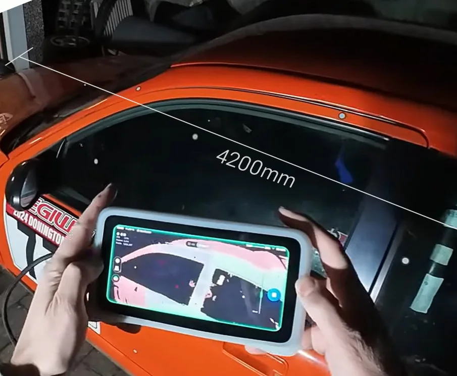 Operator scanning an orange race car with the EINSTAR Vega, live capture shown on the built-in screen