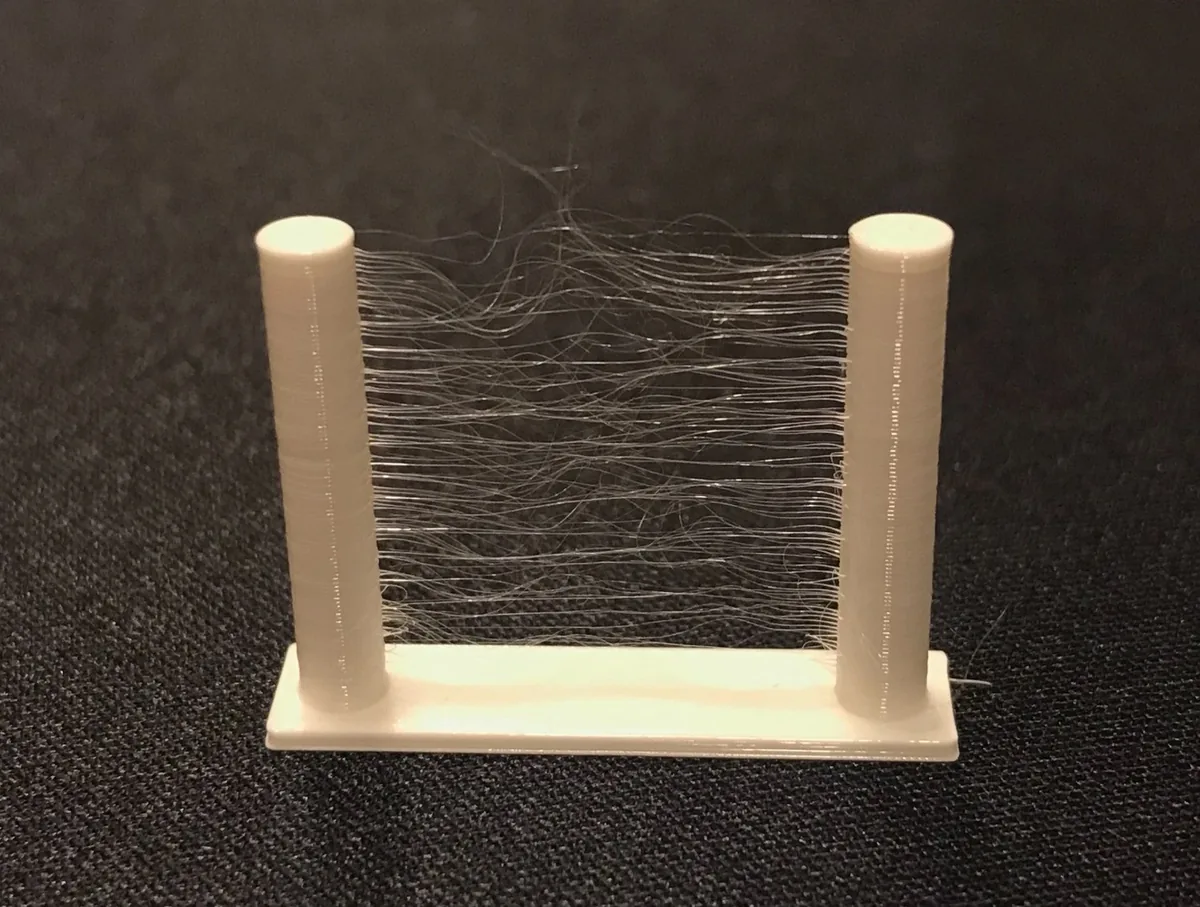 Printed retraction test towers covered in fine stringing between the posts