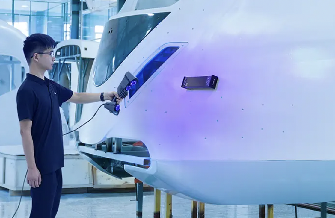 Operator using a FreeScan laser scanner on a large aircraft-fuselage panel, captured with FreeScan software