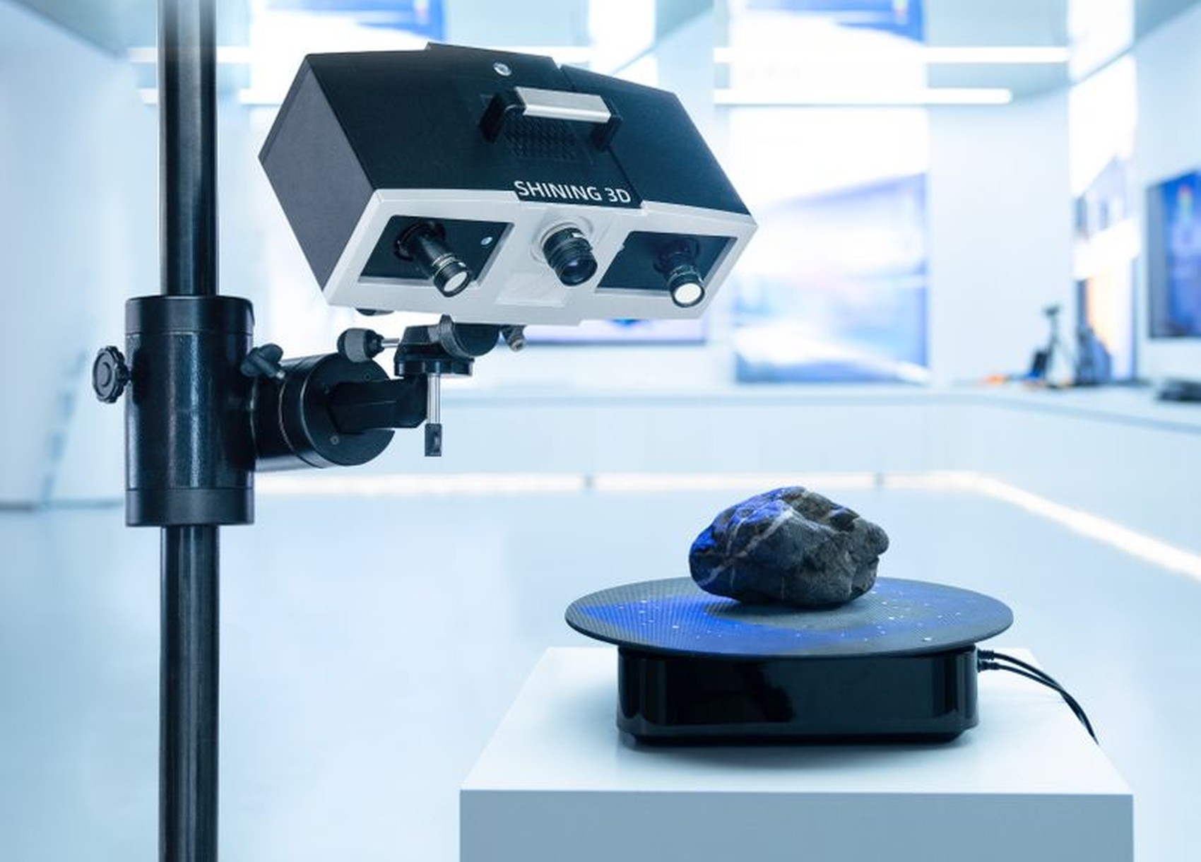 SHINING 3D OptimScan 5M Plus scanning a part on an automatic turntable in a clean metrology lab, blue LED projection