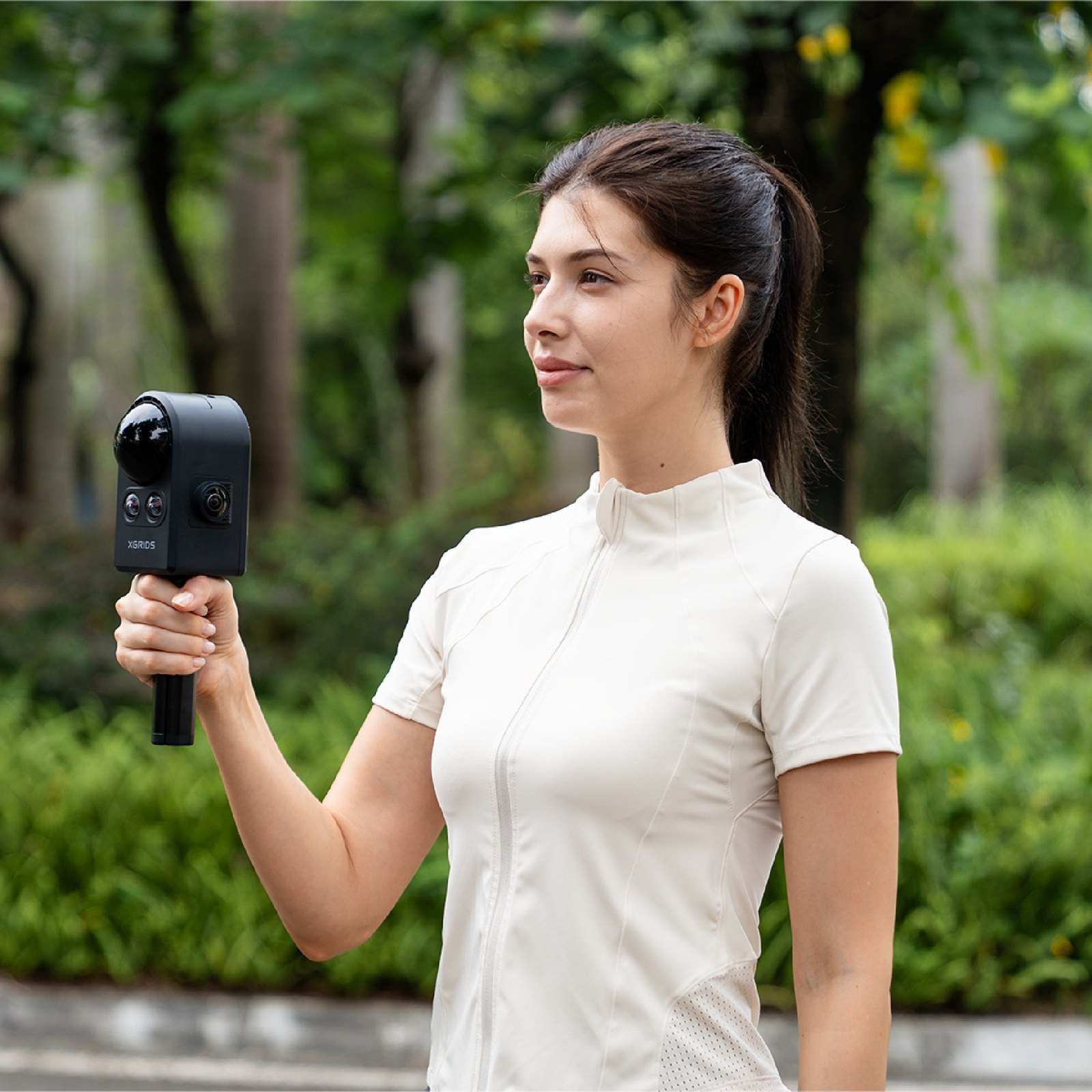 Operator capturing outdoors one-handed with the handheld XGRIDS PortalCam, dome and camera array visible